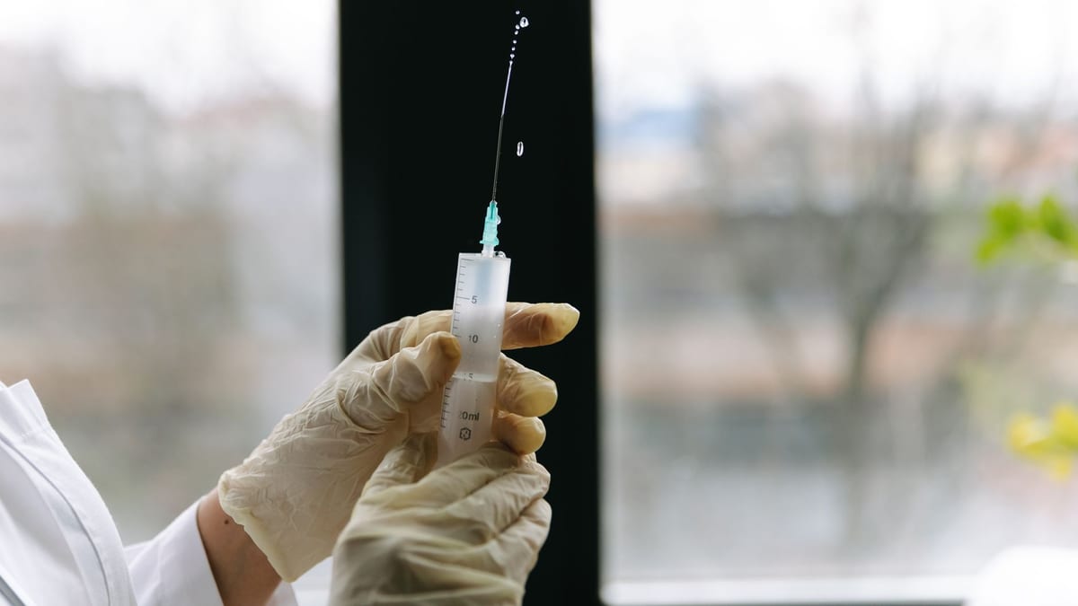 A cosmetic injector's gloved hands preparing a dermal filler syringe