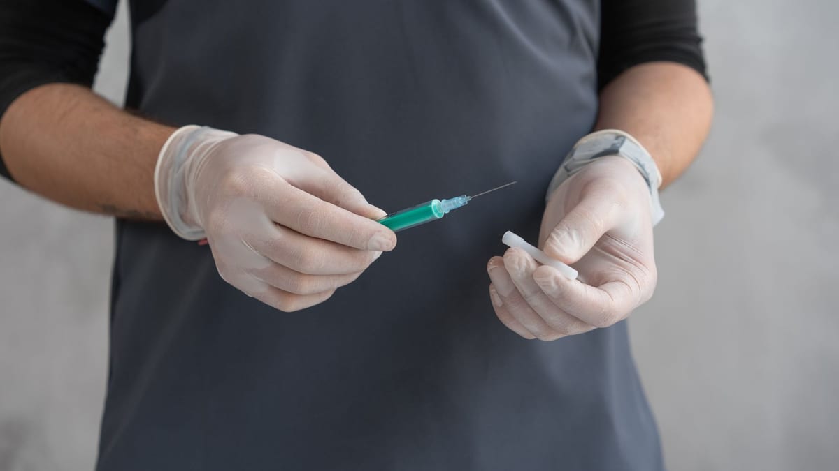 Gloved hands holding a syringe, the core tool of a nurse injector