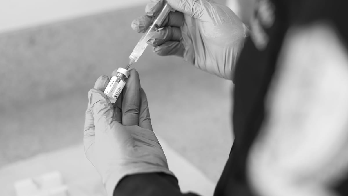 A gloved hand drawing up a neurotoxin syringe at an aesthetic clinic