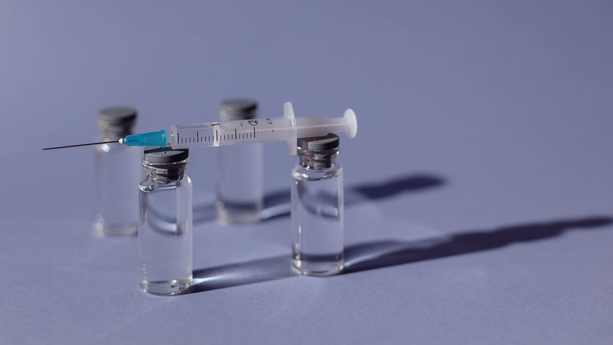 A syringe and vial on a clean white surface