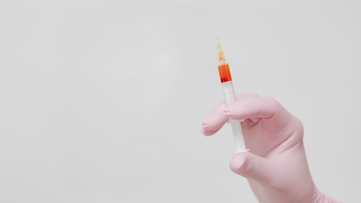 A clinician's gloved hands preparing an injection
