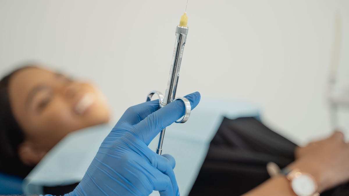 A cosmetic injector's gloved hands with a syringe at a clinic