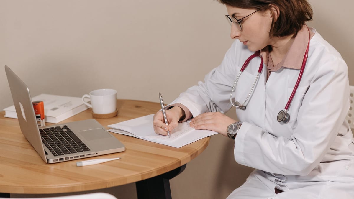 A doctor writing consultation notes at a desk, where a rhinoplasty quote is built